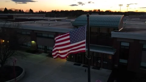American flag waving in front of school in America at night. Aerial shot Stock Footage 234981795