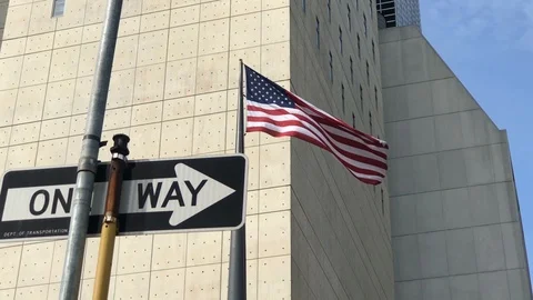 American flag waving oneway arrow sign lowering street light taxi in street NYC Stock Footage 105679355