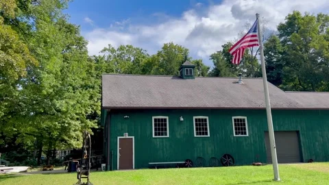 American Flag Waving on Pole in Front of Green Barn Stock Footage 345173805