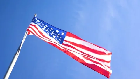 American Flag Waving in Wind with Blue Sky in Background Stock Footage 100272644