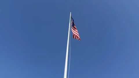 American Flag Waving in Wind on Tall Flagpole Against a Clear Blue Sky Stockbeeldmateriaal 333805558