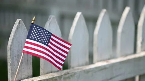 American flag waving in the wind on white picket fence Stock Footage 156667787