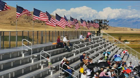 American flags fly over outdoor arena with spectators Stock Footage 68333933