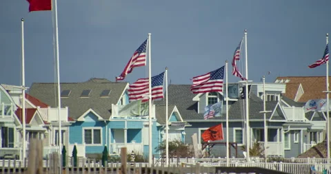 American Flags fly in strong winds, beach front homes on New Jersey Shore. Stock Footage 141708816