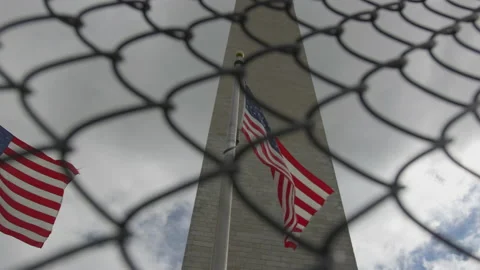 American Flags Fly Through Chain Link Fence at Base of Washington Monument Stock Footage 211869753