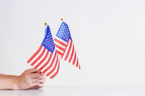 American flags in hands on a light background over the table.Stars and stripe Stock Photos