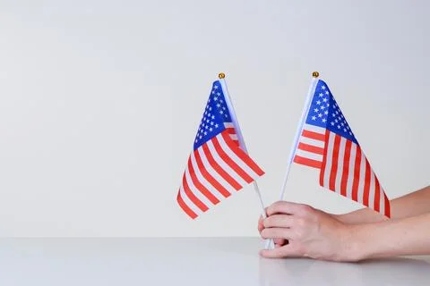 American flags in hands on a light background over the table Stock Photos