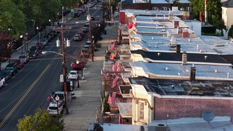 American flags hang from balconies along brick rowhouses with flat roofs in Stock Footage 340971233
