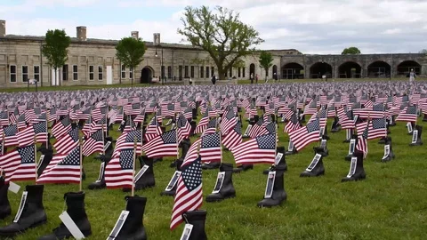 American Flags Waving in Military Boots at Memorial Site Stock Footage