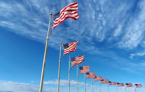 American flags waving in the wind against sky Stock Photos