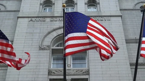 American Flags waving in the wind on the front of the Trump Hotel in DC Stock Footage 77189556