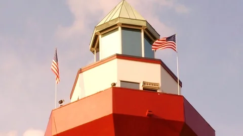 American flags waving in the wind on top of red and white lighthouse A Stock Footage 117249242