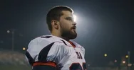 American Football Player Putting On His Protective Helmet Against Bright Stad Stock Footage