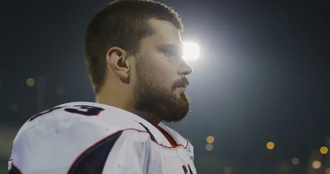 American football player putting on his protective helmet against bright stad Stock Footage