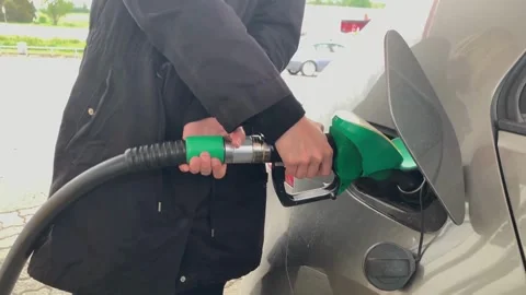 American guy holding nozzle in hand during refuel process Gasoline, gas, Stock Footage 336569380