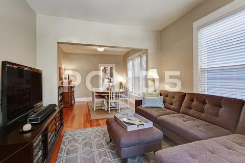 American living room interior with brown corner sofa, ottoman and black TV se Stock Photos