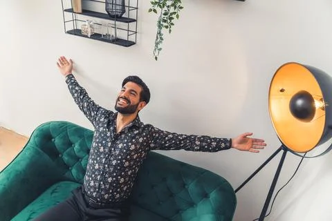 American man rejoicing while sitting on the green modern couch Stock Photos