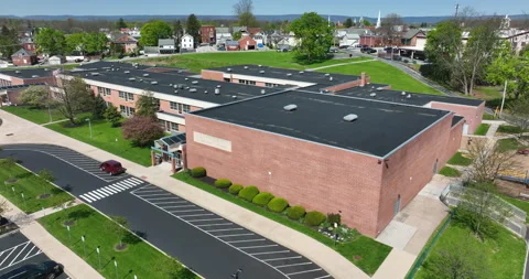 American school with flag during spring aerial in small town in USA. Stock Footage 190106254