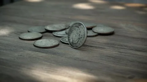 American silver coins falling in slow motion onto a wooden, rotating as they Stock Footage 136745801