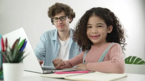 American student looking at camera while working on laptop with dad. Pedagogy. Stock Footage 283048013