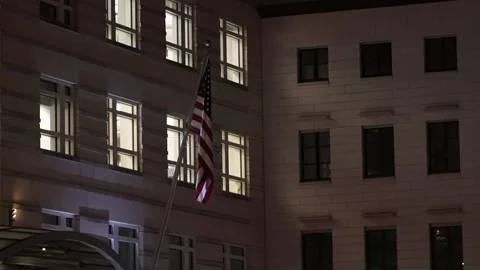American US flag on a pole wind building night berlin germany Stock Footage 228831356