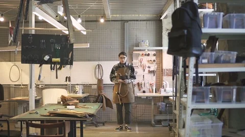 American young entrepreneur poses in workspace of modern leather workshop. Stock Footage 94757853