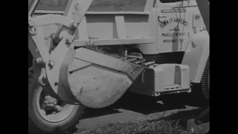 AMHERST - 1969 - A John Deere backhoe scoops soil in the middle of a sidewalk Stock Footage 340578661