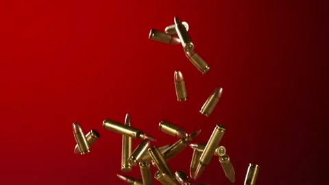 Ammunition rounds and brass shells fall against red background Stock Footage 327632380