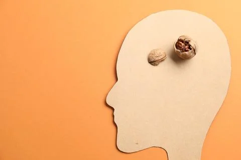 Amnesia problem. Paper cutout of human head and broken walnut on orange bac.. 库存照片