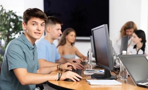 Among students of computer academy programmers, young guy is sitting and smiling Stock-Fotos