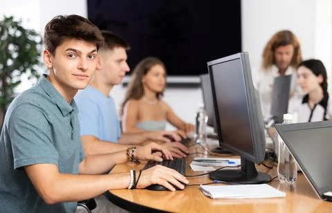 Among students of computer academy programmers, young guy is sitting and smiling Stockfoto's