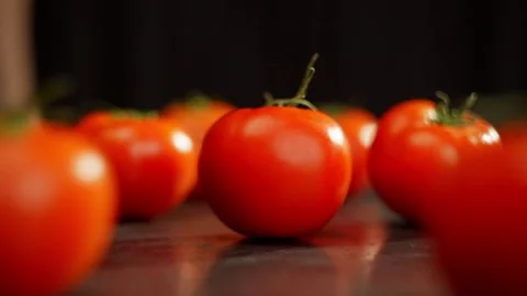 Among the tomatoes spread out on the table, one rotates around itself. Video stock 269036276