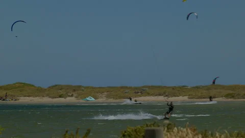 Amongst many sails a kite surfer drops from great height and speeds off Stock Footage 229458863
