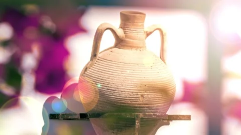 Amphora with two handles hanging on wall with a blurred bourgainvillae Stock Footage 148670741