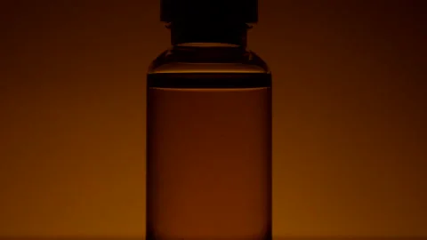 An ampoule with a cure for covid 19 stands on yellow background on the table Stock Footage