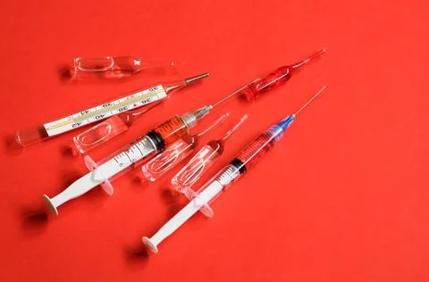 Ampoules and syringes on red background Stock Photos
