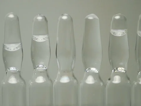Ampoules with a clear solution for injection stand in a row. panning close-up Stock Footage 84853094
