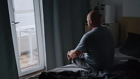 Amputee Man Sitting on Bed Putting On Prosthetic Leg by Window Stock-Footage 317974804