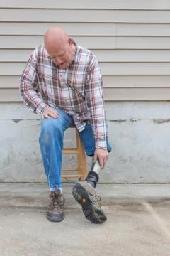 Amputee man sitting on stool turning his prosthetic leg around Stock Photos