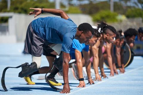 Amputee sprinters ready at starting line on sunny sports track Stock Photos