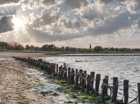 Amrum, Germany - dramatic sunset with shore in foreground and small village Stock Photos