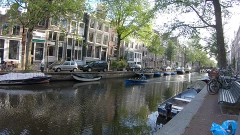 Amsterdam small boat sailing down a canal with old buildings in background Video stock 131827511