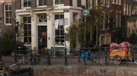 Amsterdam - Typical street, sight of cafe. Woman on bike. Stock Footage 12801178