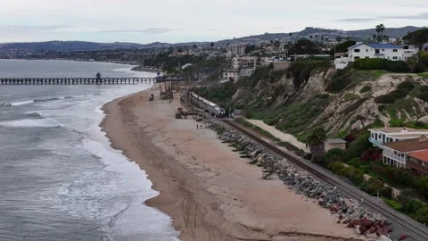 Amtrak surfliner train passing beach cliffs and pier in aerial Southern 스톡 동영상 332599125
