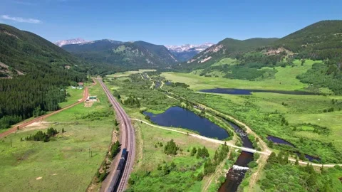 Amtrak Zephyr train passing through Rocky Mountains - aerial follow Video stock 157932786