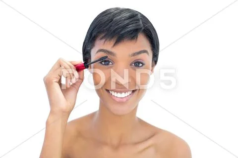 Amused black haired woman applying mascara Stock Photos