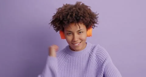 Amused happy curly haired Afro American woman enjoys good sound quality listens Stock Footage 144457416