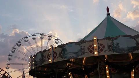 Amusement park carousel and ferris wheel at sunset 스톡 동영상 340280859