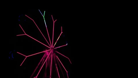 An amusement park. Multi coloured Ferris wheel rotates at night. Bright neon glo Stockbeeldmateriaal 106889405