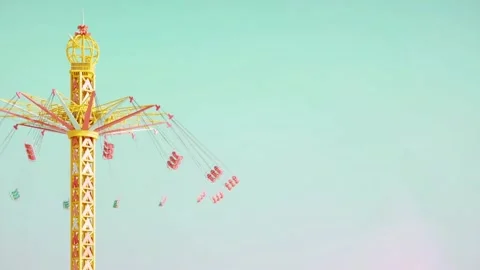 Amusement park ride with empty seats spinning high in the air against clear.. Stock Footage 346392919